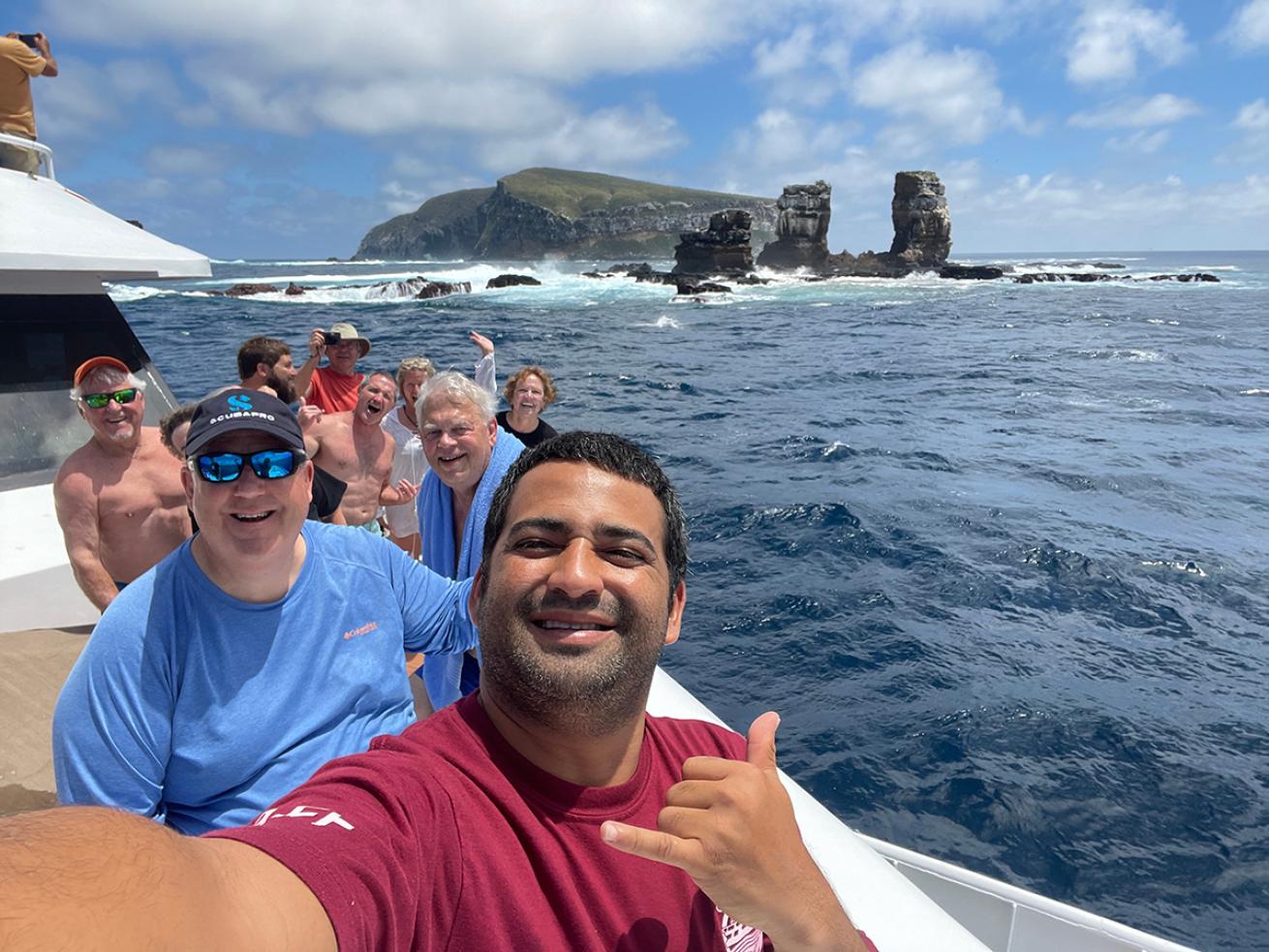 Group stands on a boat in front of the collapsed Darwin's Arch
